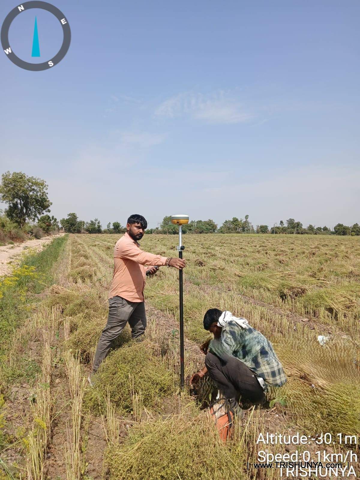 Surveyor taking a DGPS reading while assistant marks the point on site amid dense bushes along the corridor