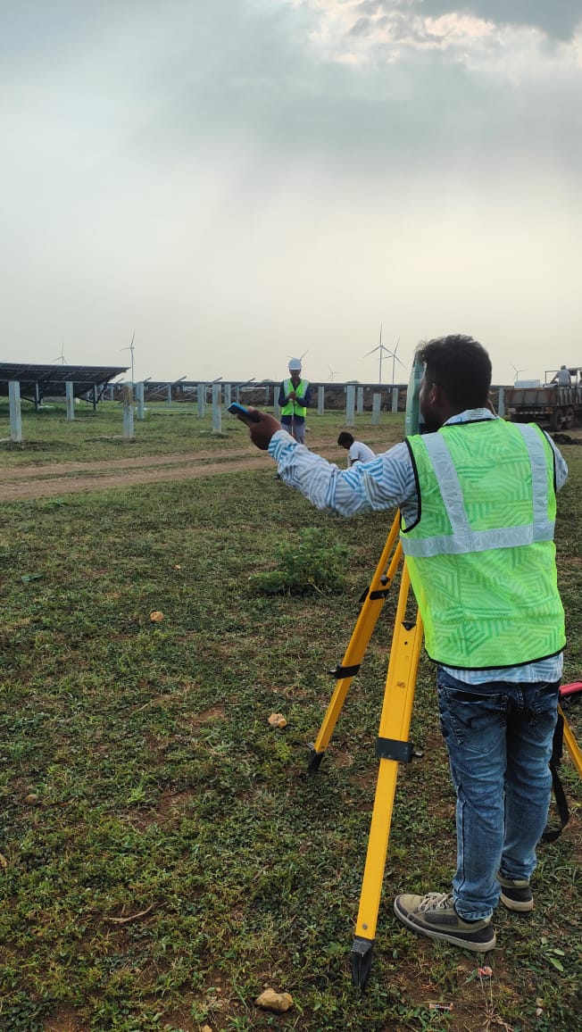 Surveyor instructing prism holder to align position for solar panel post stakeout