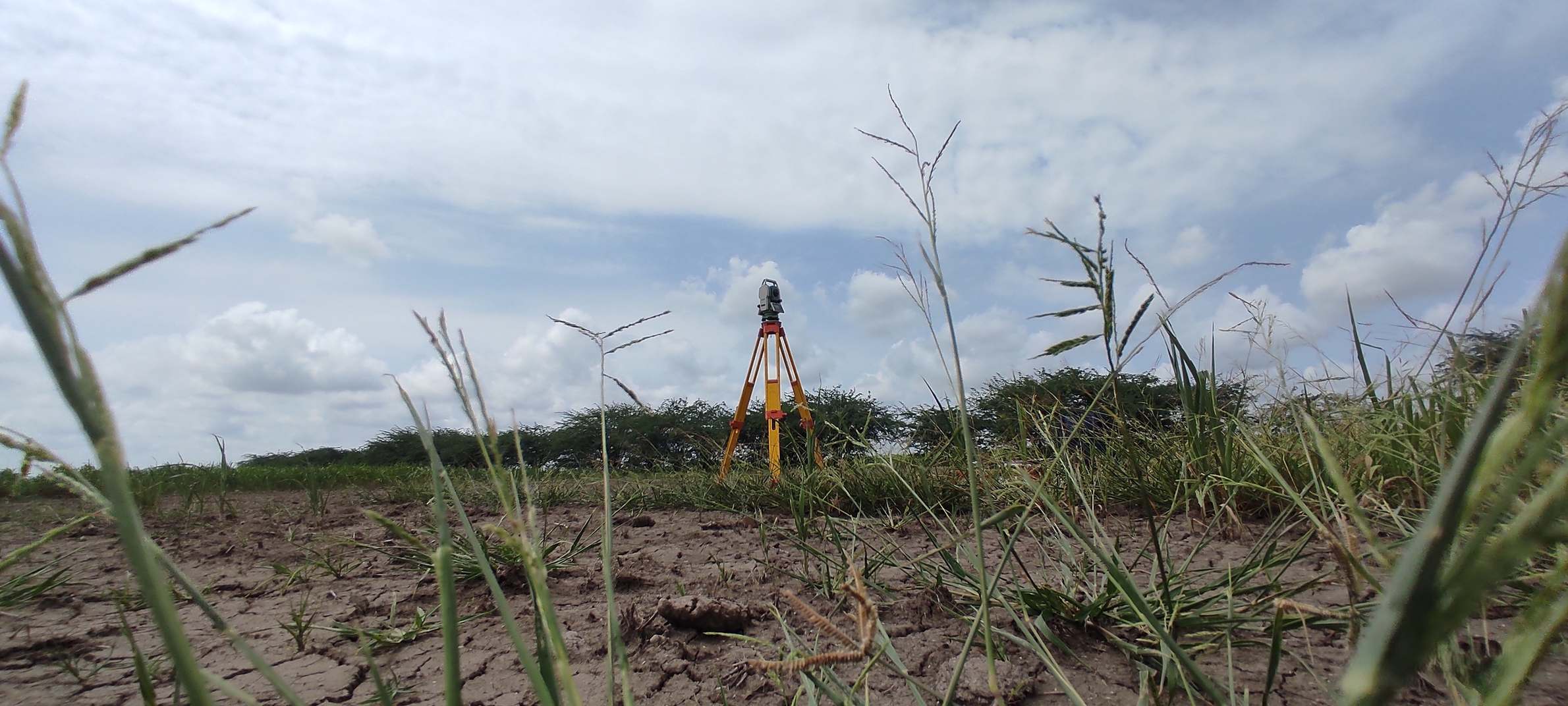 Geometra che utilizza una Total Station durante un rilievo di confine di terreno aperto